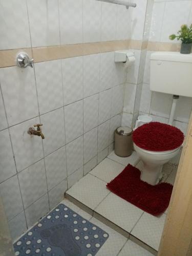 a bathroom with a toilet with a red rug at Mo Homes - Studio 2 in South B, 15mins from JKIA, Wilson Airport & Nairobi CBD in Nairobi