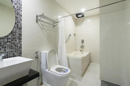 a white bathroom with a toilet and a sink at Hotel Dreamworld North Edsa in Manila