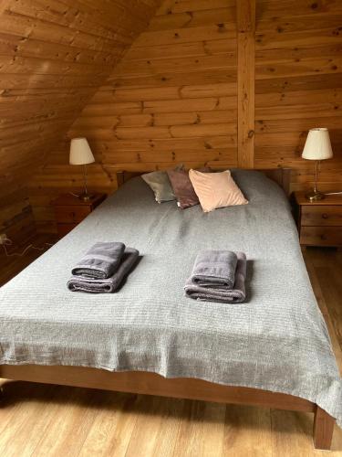 a bed in a wooden room with towels on it at Litewska Chata in Sejny