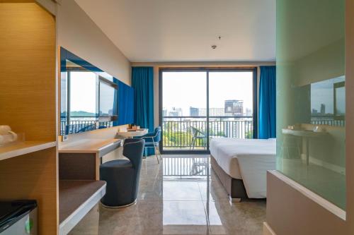 a hotel room with a bed and a balcony at Pattaya Discovery Beach Hotel - SHA Extra Plus in Pattaya Central