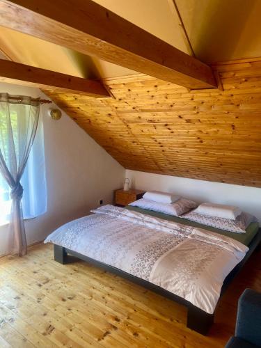 a bed in a room with a wooden ceiling at Chata Roda s vnitřní saunou in Rabyně