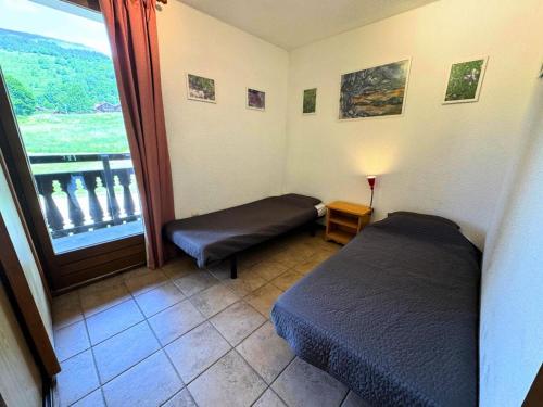 Cette chambre comprend deux lits et une grande fenêtre. dans l'établissement Résidence Gentianessmb - 2 pièces 4 pers. en face du télécabine de St Martin de Belleville MAE-3964, à Saint-Martin-de-Belleville