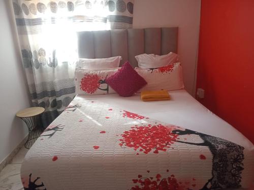 a bedroom with a bed with red and white sheets and pillows at Neo & Ruks Guest Houses parow 4 in Avondale