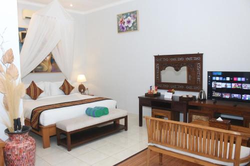 a bedroom with a bed and a desk and a television at The Manja Retreat Lovina in Buleleng