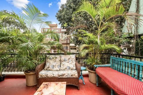 un balcon avec un banc et des palmiers dans l'établissement Vintage Haven Leafy Getaway Luxury Villa in Indiranagar by Spacez, à Bangalore