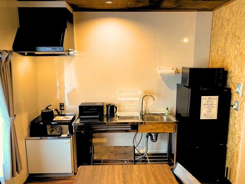 a small kitchen with a sink and a refrigerator at Guest House -海- in Takamatsu