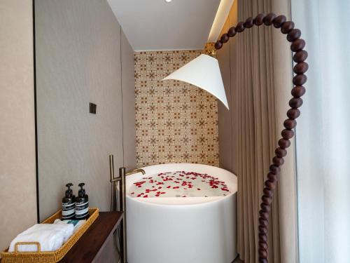 a bathroom with a white tub with red flowers on it at 浮生居设计师民宿 in Yining Airport