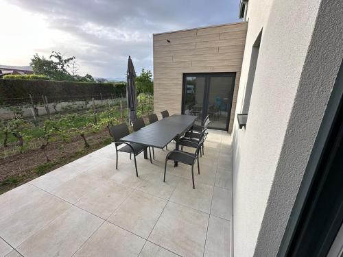 Une table à manger et des chaises sont disponibles sur la terrasse. dans l'établissement COLMARandCo au coeur des vignes, à Ingersheim