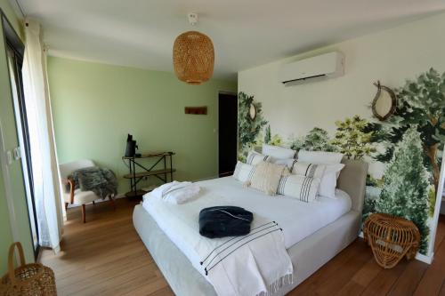 a bedroom with a white bed with a black bag on it at Les Suites in Camiers
