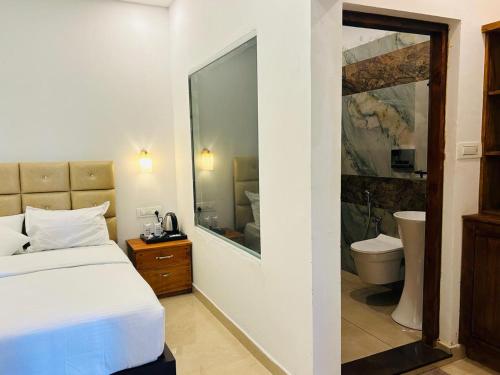 a bedroom with a bed and a bathroom with a toilet at Lavilla Lake Resort And Restaurant in Kollam