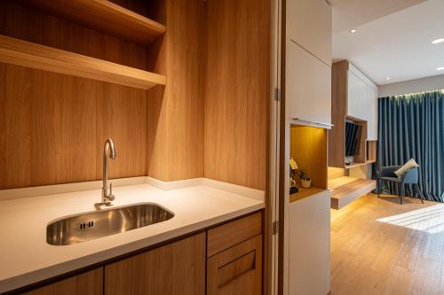 a kitchen with a sink and a living room at Sunbeam Hotel Pattaya in Pattaya Central