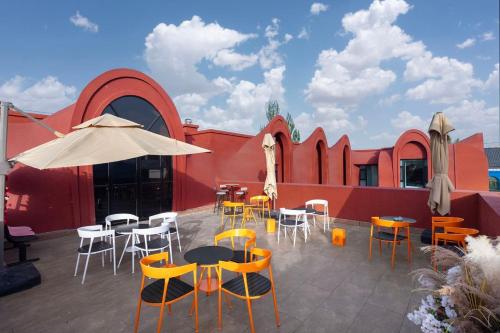 a patio with chairs and tables and an umbrella at 浮生居设计师民宿 in Yining Airport