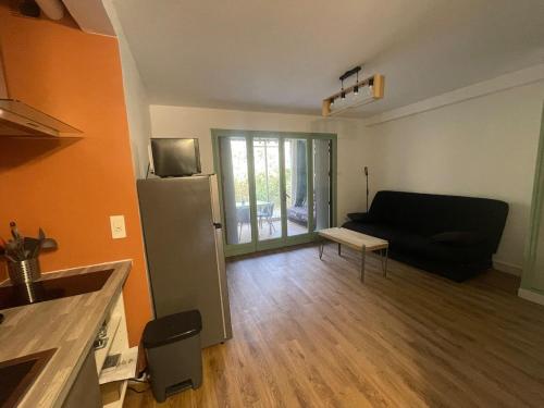 - un salon avec un canapé noir et un réfrigérateur dans l'établissement Cozy Gardeen Studio, à La Garde