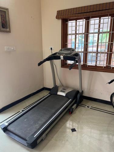 a gym with a treadmill in a room with a window at Eden luxury stay Coimbatore in Coimbatore