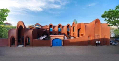 an orange building with a blue door in a parking lot at 浮生居设计师民宿 in Yining Airport