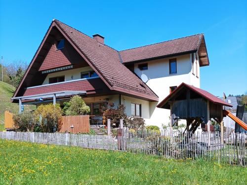 a house with a brown roof and a fence at Ferienwohnung Wiesenblick in Oberharmersbach