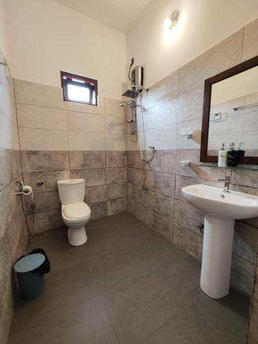 a bathroom with a toilet and a sink and a mirror at The Residence by Amaya in Anuradhapura