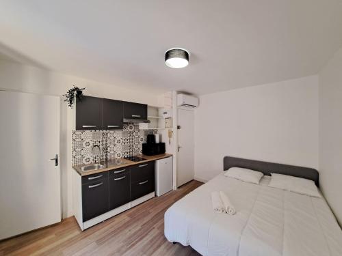 une chambre avec un grand lit blanc et une cuisine dans l'établissement Palerme - City Appart, à Reims