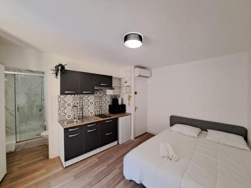Cet appartement comprend une chambre avec un lit blanc et une cuisine. dans l'établissement Palerme - City Appart, à Reims