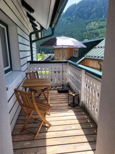 a wooden balcony with a chair and an umbrella at Apartmenthaus Edelweiss in Gosau in Gosau