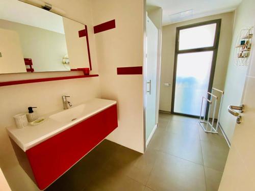 La salle de bains est pourvue d'un lavabo rouge et d'une fenêtre. dans l'établissement Les Poissons Rouges, à Pérols