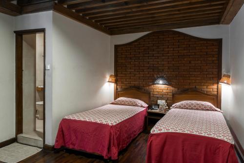 a bedroom with two beds and a brick wall at Kantipur Temple House in Kathmandu