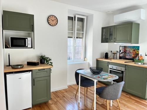Una cocina con gabinetes verdes y una mesa pequeña. en La cigogne rêveuse, en Ensisheim