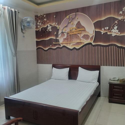 a bedroom with a bed with a poster on the wall at KHÁCH SẠN MlLAN in Dĩ An