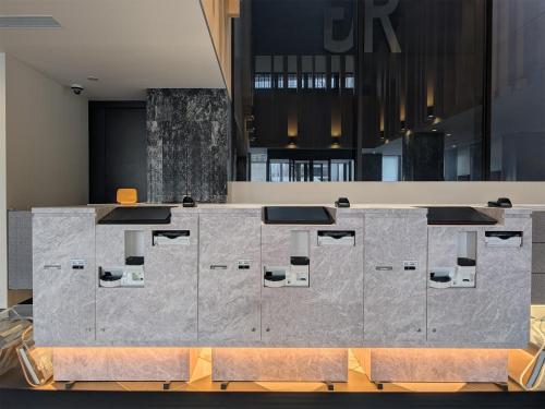 a lobby with a large concrete counter with chairs at Green Rich Hotel Kurume Natural Hot Spring Arimamutsumonnoyu in Kurume