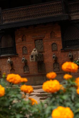 a brick building with some orange flowers in front of it at Kantipur Temple House in Kathmandu