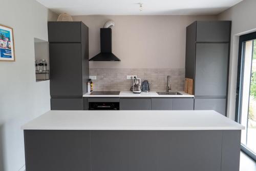 une cuisine avec des armoires noires et un comptoir blanc dans l'établissement Joli Villa à 10 min de la plage, à Grimaud