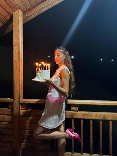 a woman is holding a birthday cake with lit candles at LIVANi in Batumi