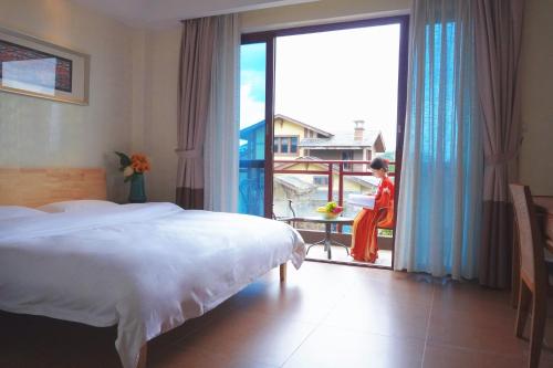 a bedroom with a bed and a woman looking out the window at Avatar Valley Villas in Zhangjiajie
