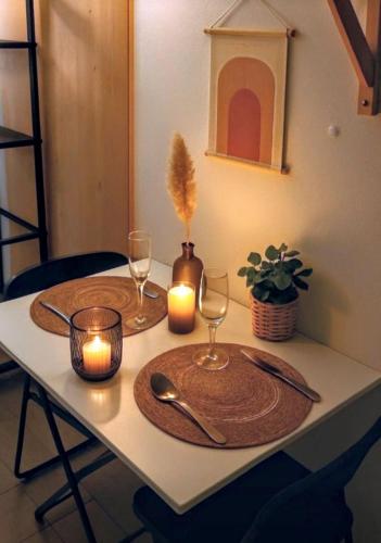 une table avec une bougie et deux assiettes et verres dans l'établissement Studio cosy Paris Centre, à Paris