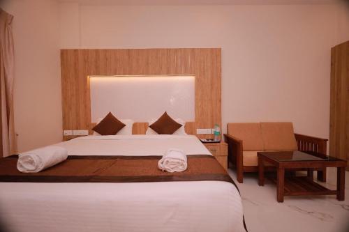 a bedroom with a large white bed and a chair at Hotel Sahaya Arasi in Kovakulam
