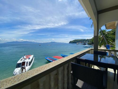 a balcony with a boat in the water at Lalaguna Villas Luxury Dive Resort and Spa in Puerto Galera