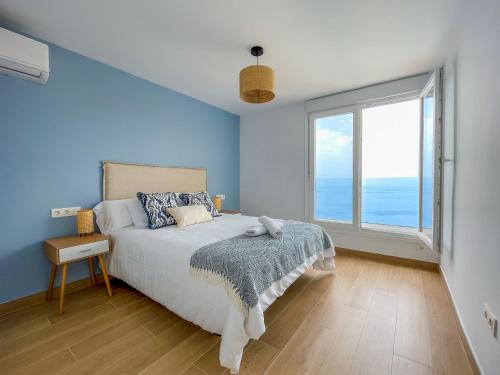 a blue bedroom with a bed and a large window at Ocean views from every corner in Almería