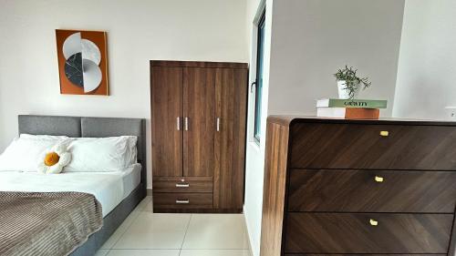 a bedroom with a bed and a wooden cabinet at Tulip Residences by Manhattan Group in Shah Alam