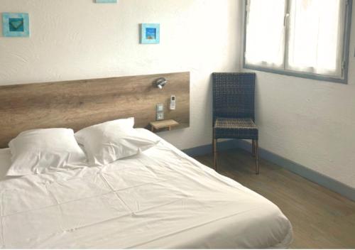 a bedroom with a white bed and a chair at Hôtel Le Carnon in Carnon-Plage