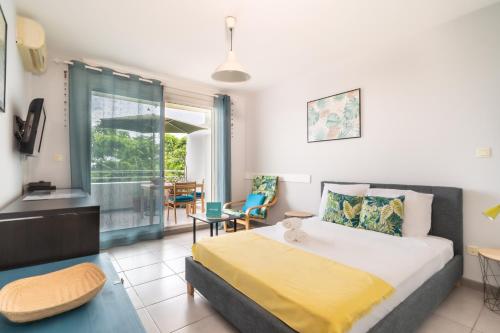 a bedroom with a large bed with a yellow blanket at FLAMBOYANT - Studio 2 personnes avec lit de qualité hôtelière séparable pour couple ou amis avec très belle terrasse à 12 min à pied ou 4 min en voiture du lagon de l'Ermitage - ST GILLES LES BAINS in La Saline les Bains