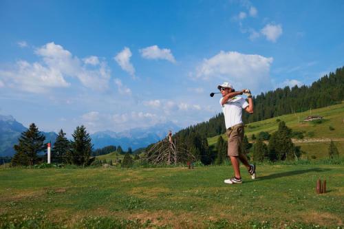 a man swinging a golf club in a field at Mountain view Balcony et comfort in Ollon