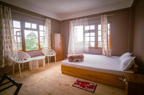 a bedroom with a large bed and two windows at Keanas Lamahatta Homestay By StayApart in Takdāh