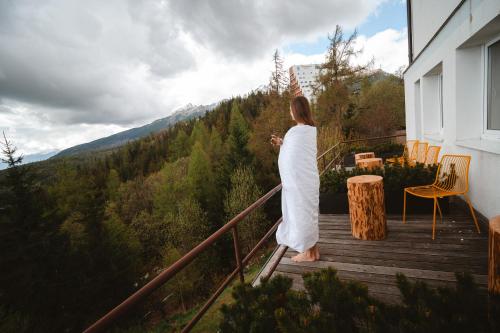 a woman standing on a balcony looking at the mountains at Vila Emma in Štrbské Pleso
