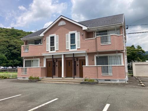 a large pink house with a parking lot at メゾンド寺田 アパート1室貸切 素泊まり最大6人宿泊可能 4名様まで同一料金 in Yamaguchi
