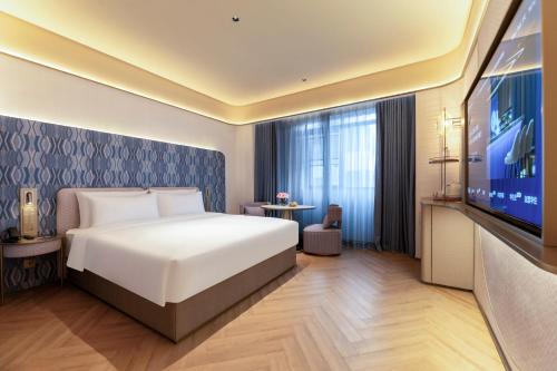 ein Schlafzimmer mit einem Bett und einem Flachbildfernseher in der Unterkunft Changzhou Railway Station Qingguoxiang Manxin Hotel in Changzhou