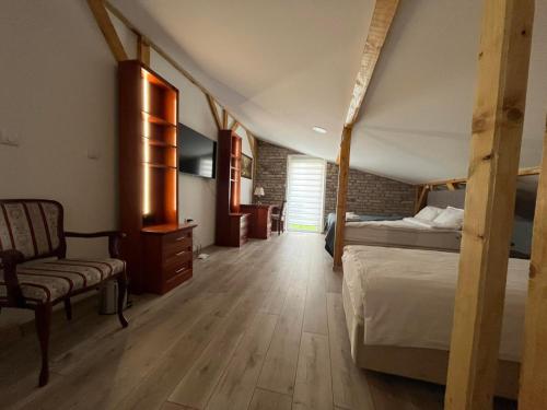 a bedroom with two beds and a chair in a room at Moja Mona in Subotica