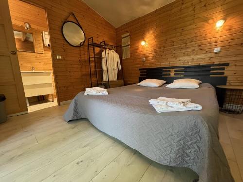 a bedroom with a large bed and a mirror at Les Cabanes du Lac - SPA - Petit Déjeuné - Cabane du frêne & Cabane du chêne Premium in Sévignac-Thèze