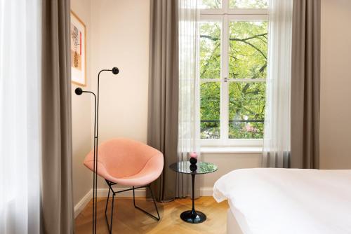 a bedroom with a bed and a chair and a window at ESPLANADE Saarbrücken in Saarbrücken