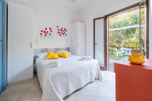 Dormitorio blanco con cama con almohadas amarillas en Il Giardino Dei Gelsi Otranto, en Otranto