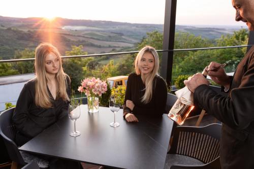two women sitting at a table with wine glasses at Pećina Stroga - Bjelica Winery Rooms in Sremski Karlovci